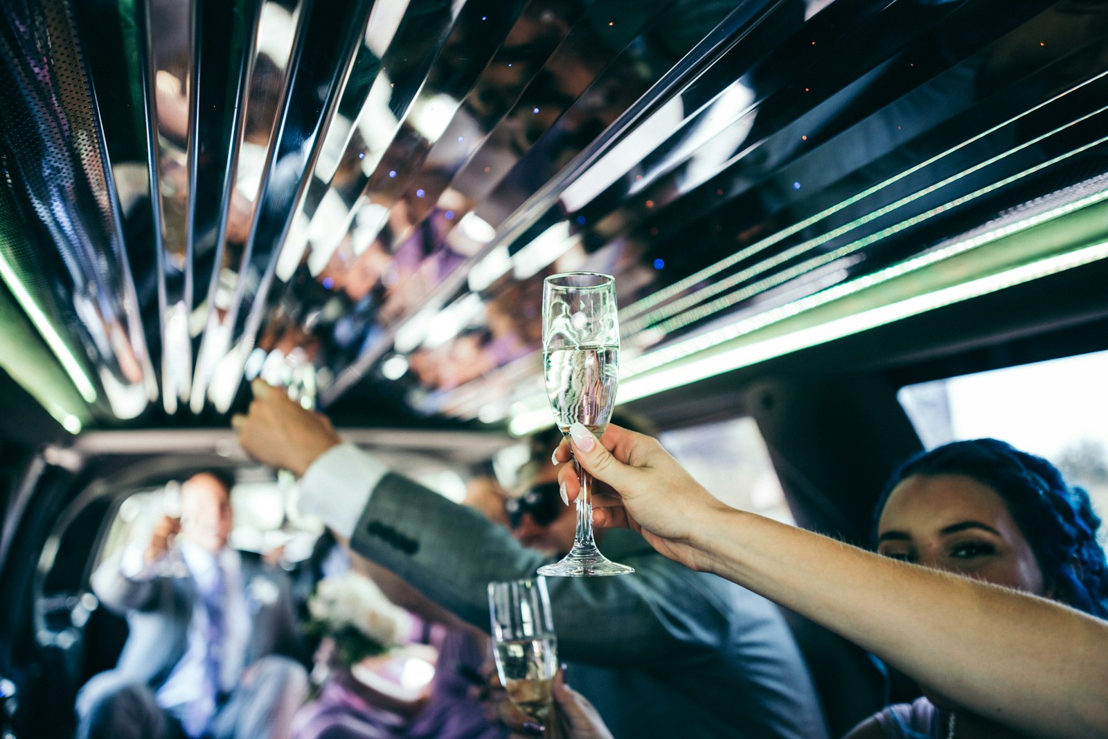 Guests raising champagne glasses under the mirrored ceiling of a stretch limousine