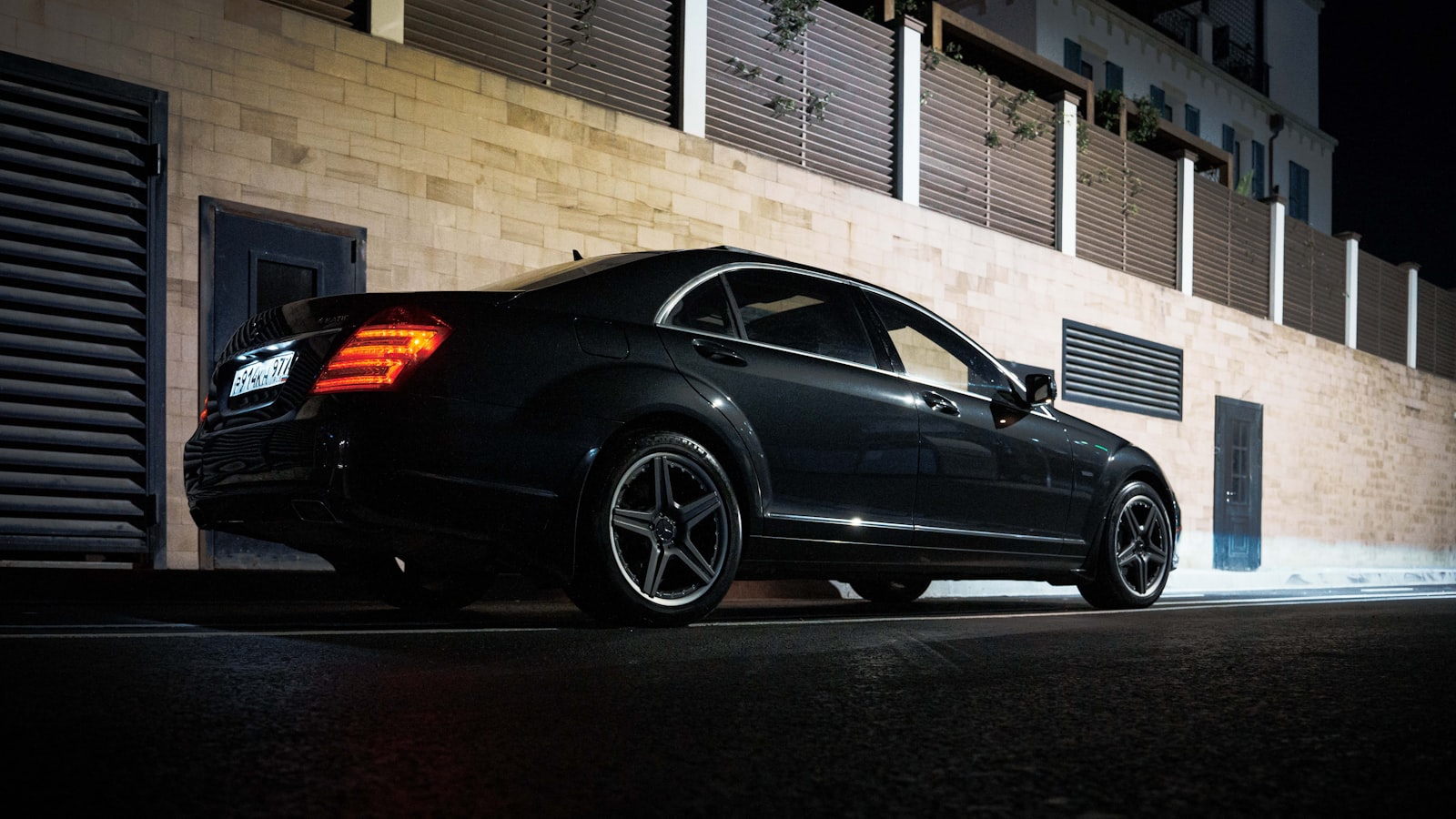 Black Mercedes-Benz luxury sedan on a rain-slicked street at night