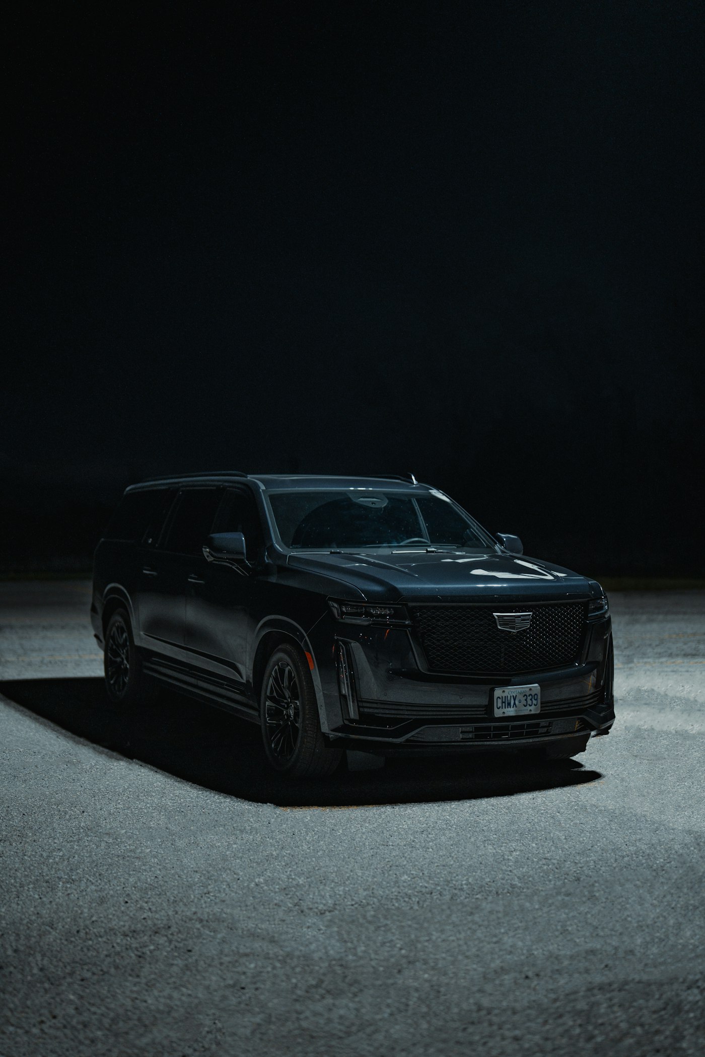 Black Cadillac Escalade under a single light at night